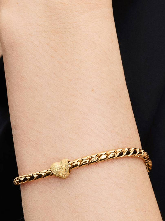 Gold bracelet on a wrist with a black background
