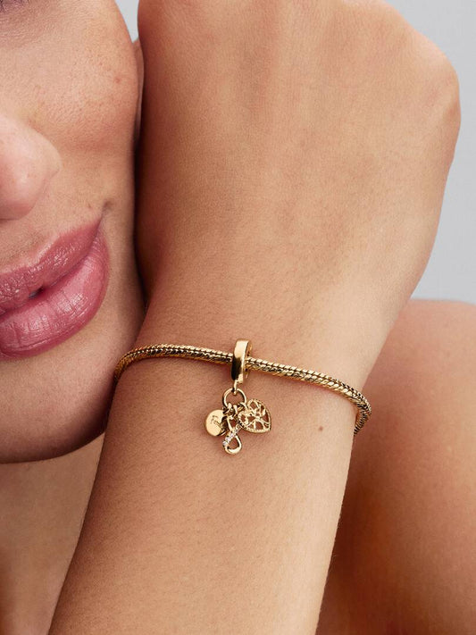 Gold bracelet with charms on a wrist against a neutral background