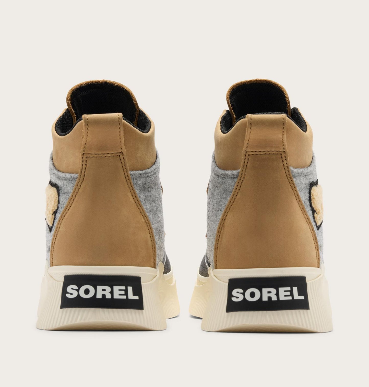 A pair of Sorel high-top sneakers shown from the back, featuring tan leather panels, a gray felt side panel, a beige sole with a black SOREL logo patch, and a small embroidered bear face on the heel.