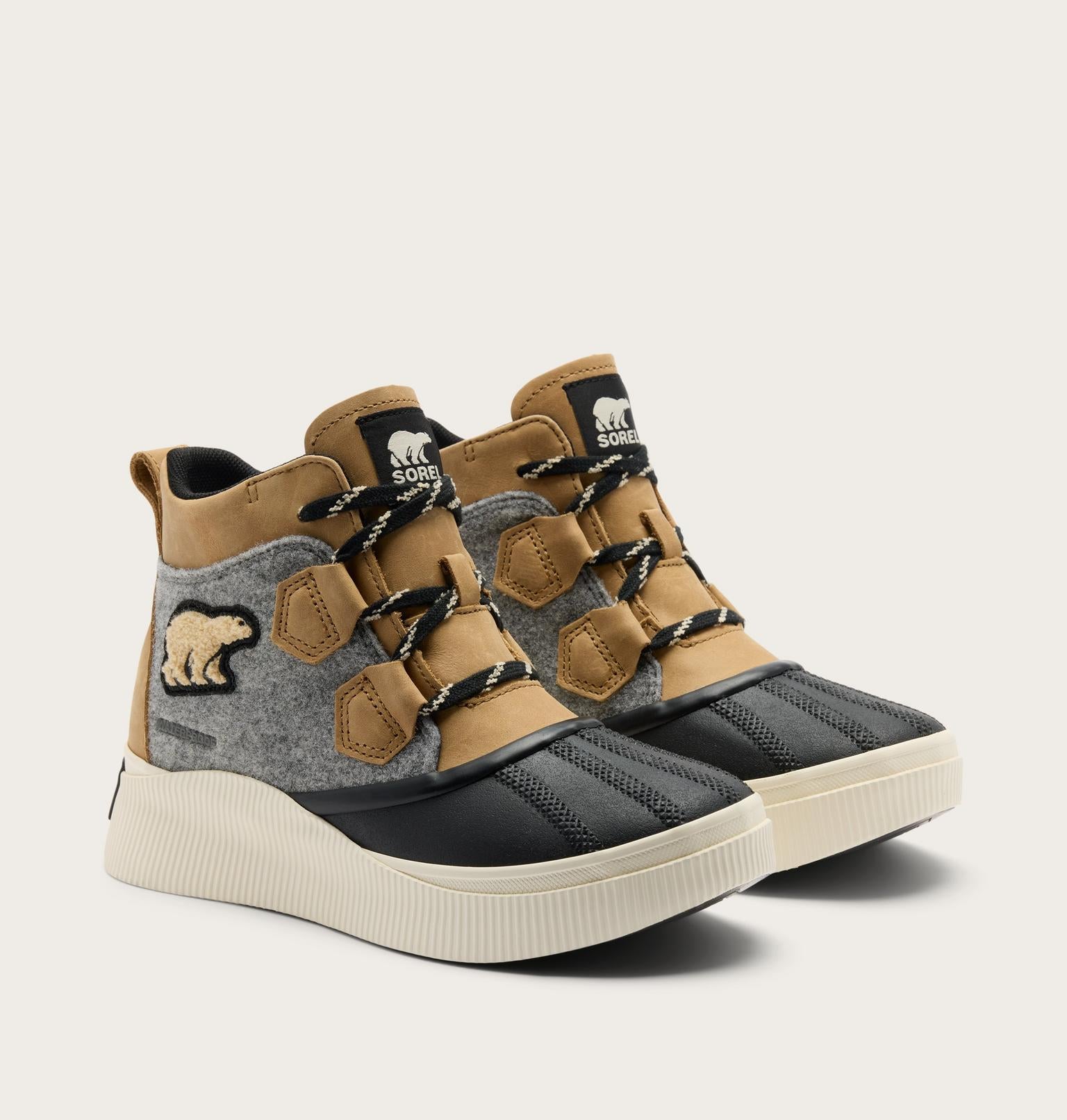 A pair of high-top winter sneakers from Sparta, featuring tan suede overlays, a gray felt side panel with a bear patch, black toe caps, and thick cream platform soles, set against a light beige background.