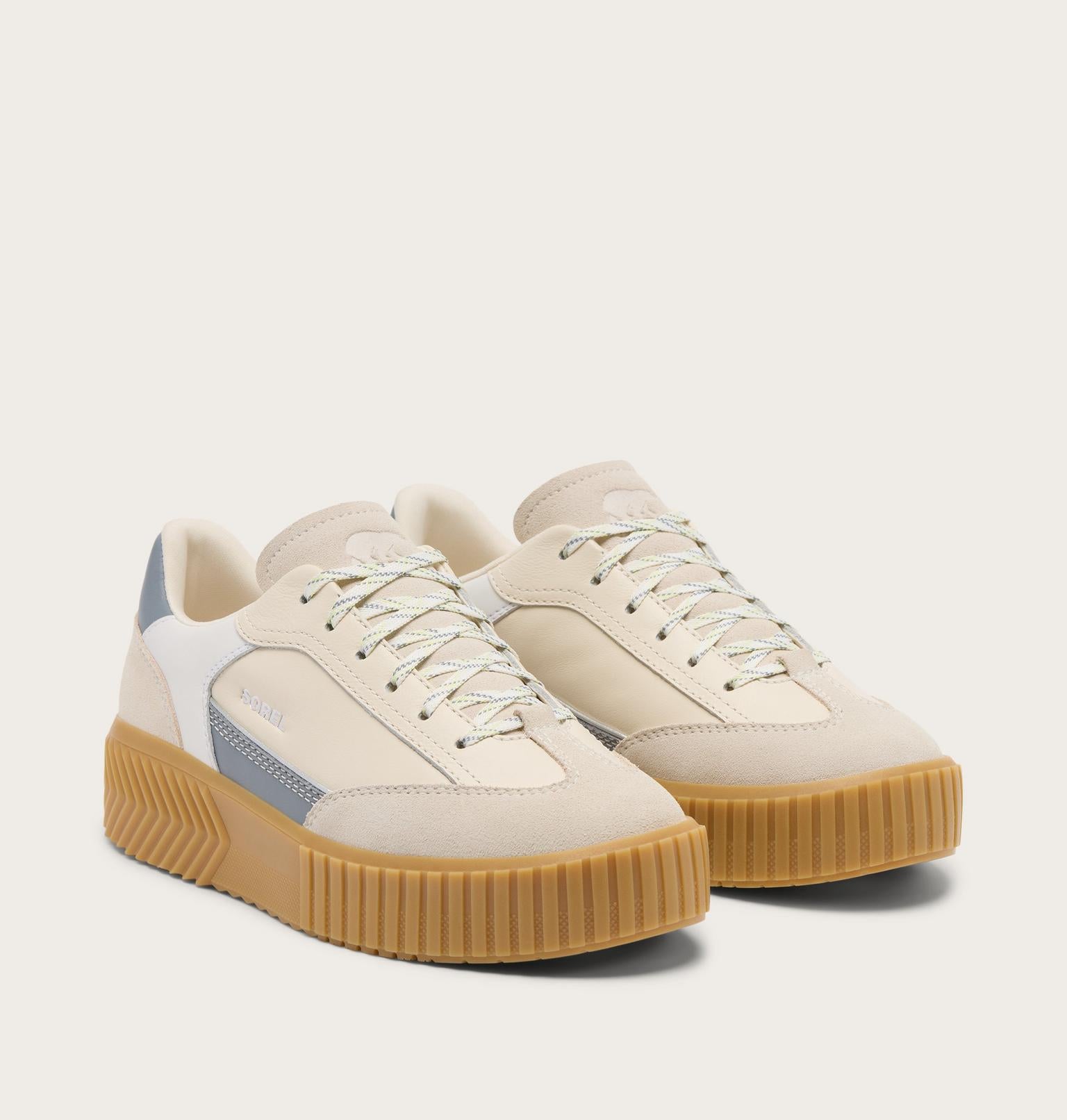 Pair of beige sneakers with brown soles on a white background