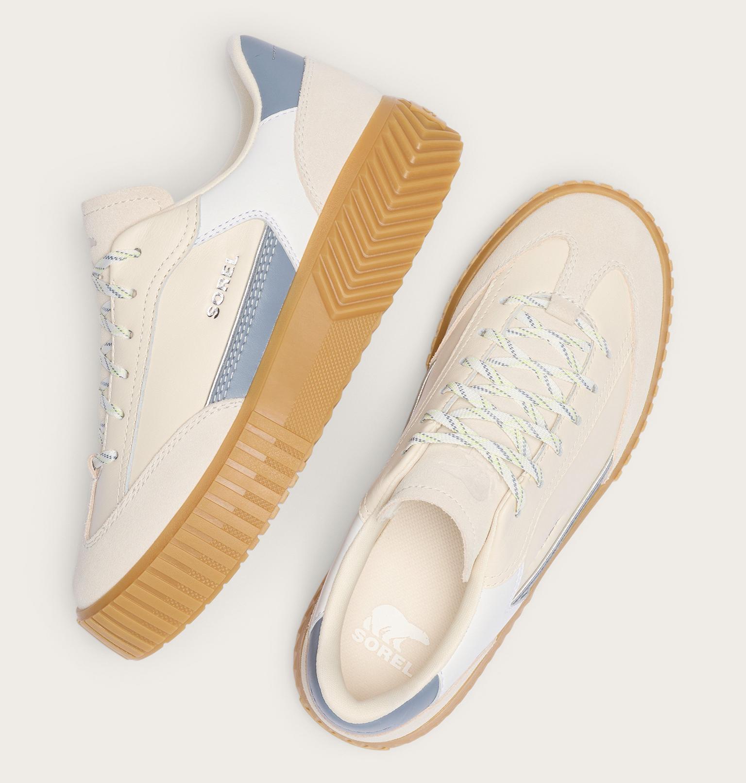 Pair of cream sneakers with brown soles on a light gray background