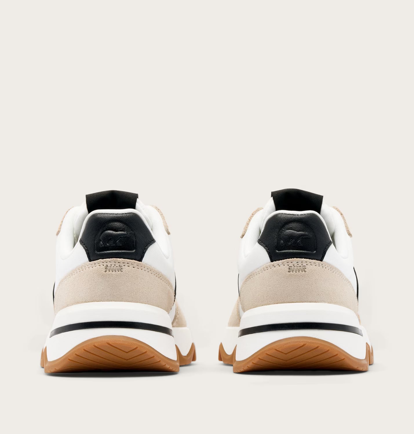 Pair of white and beige sneakers with black accents on a light gray background