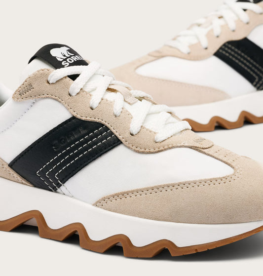 Close-up of a white, beige, and black sneaker with brown accents on a white background.
