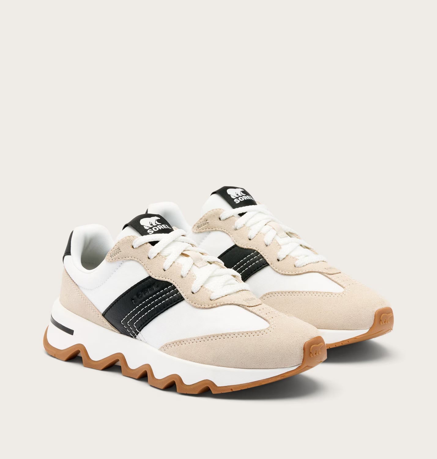 Pair of white and beige sneakers with black accents on a light gray background