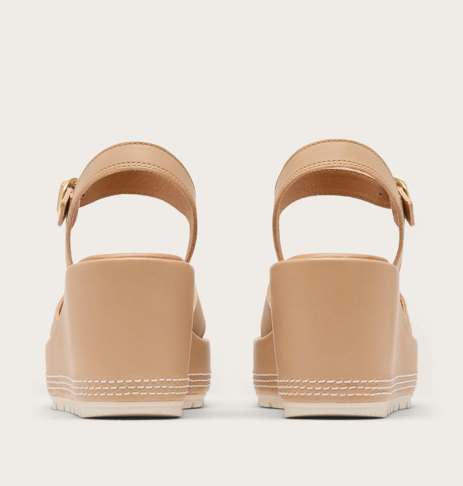 Pair of tan sandals with a white background