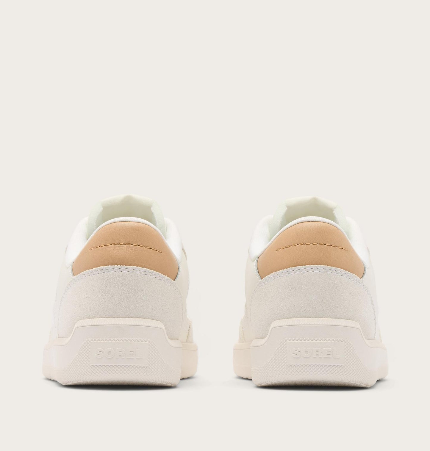 White sneakers with tan accents on a light gray background