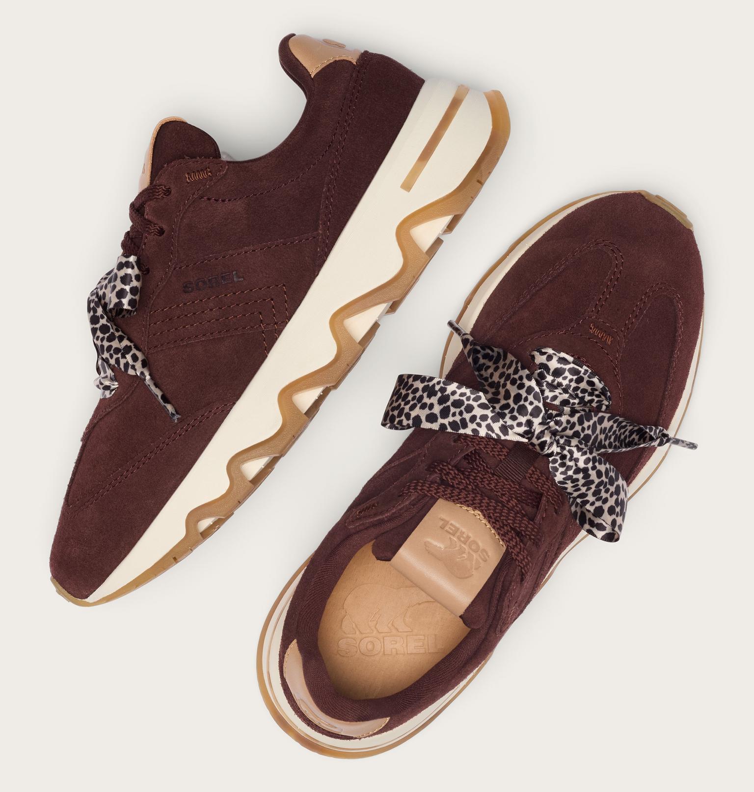 A pair of dark brown suede sneakers with wavy cream and gum soles, featuring leopard-print ribbon laces, shown from multiple angles on a light beige background.