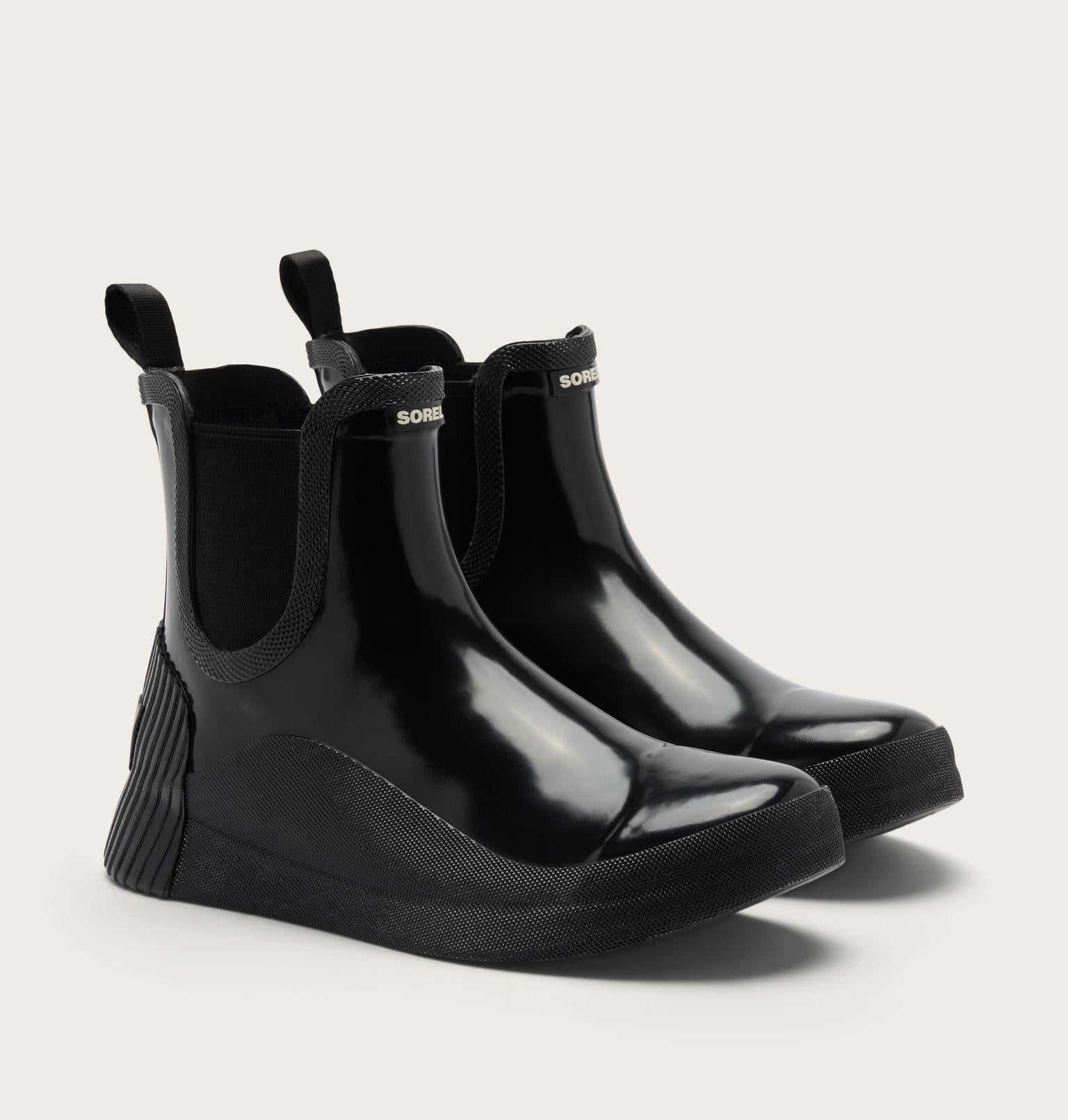 A pair of glossy black rubber rain boots with elastic side gore panels and pull tabs, shown on a light gray background.