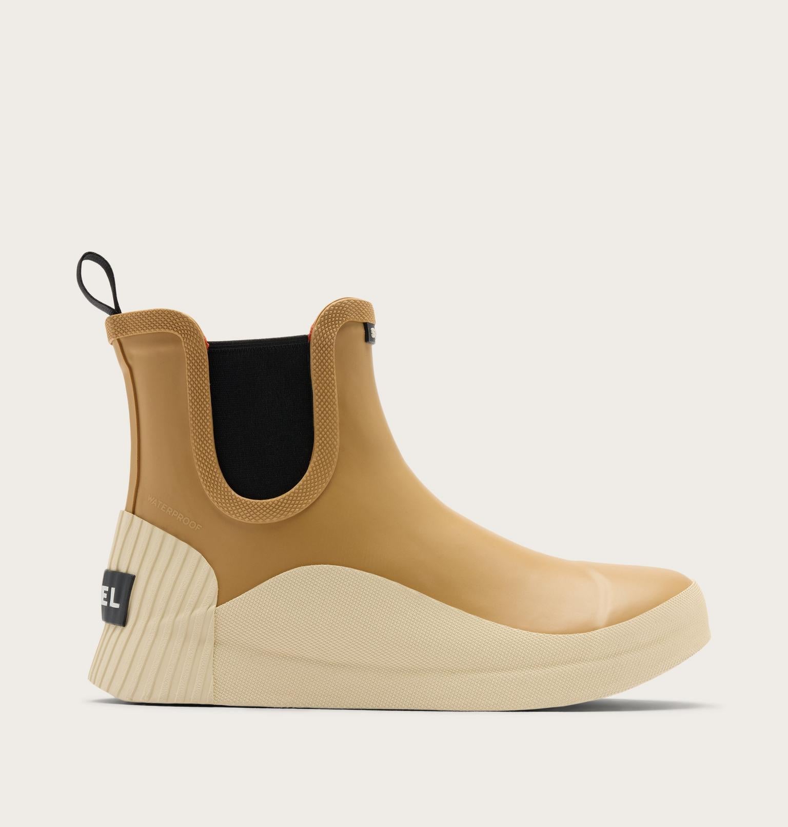 A single Chelsea-style ankle boot in tan and cream with a black elastic side panel and a black heel tab, shown in profile against a light beige background.