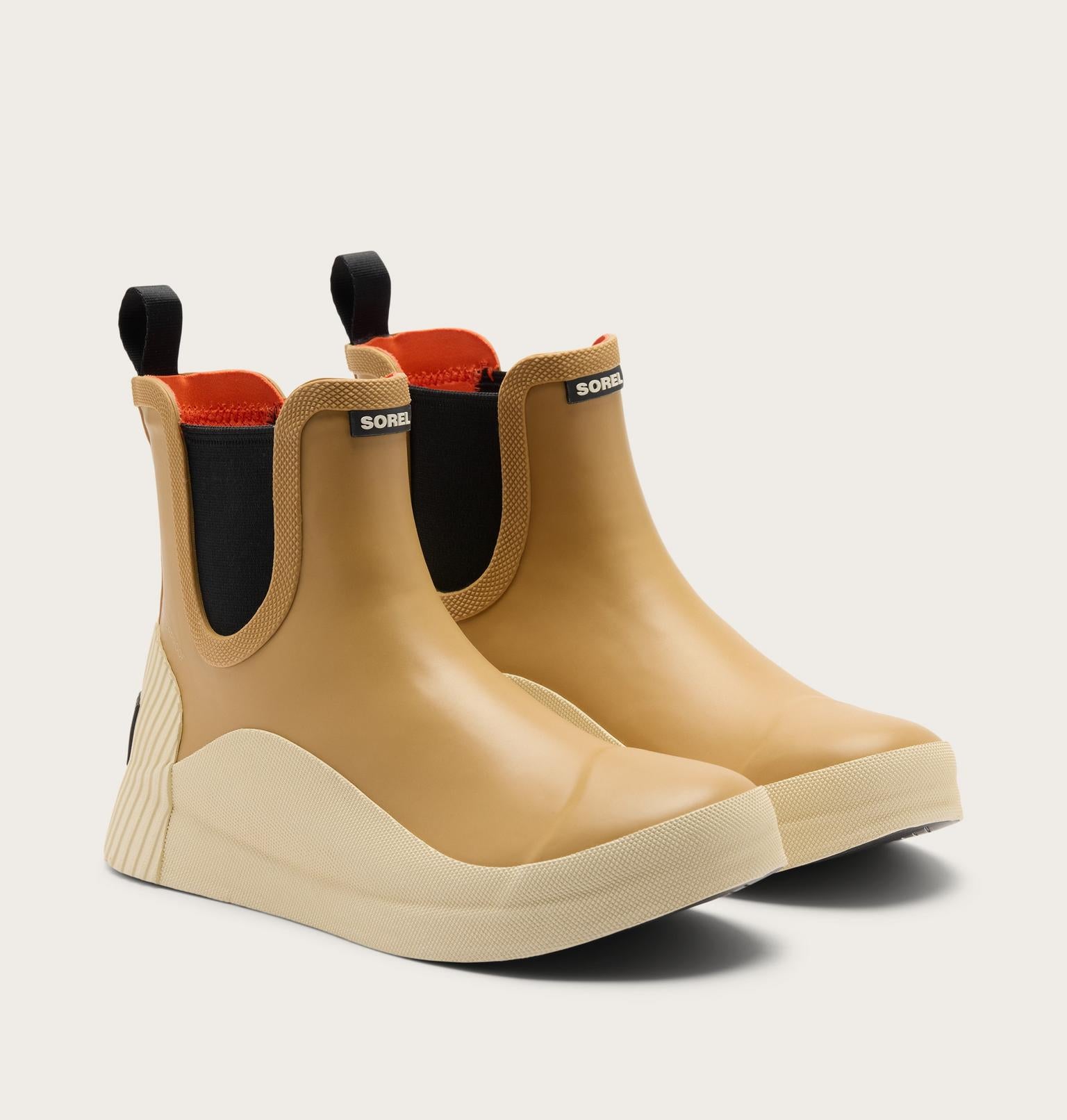 A pair of beige rubber rain boots with black elastic side panels, black pull tabs, and a cream-colored wedge sole, shown on a light gray background.