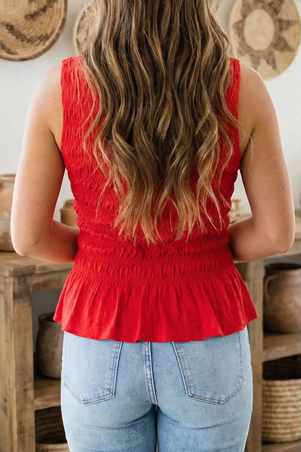 Person wearing a red top and blue jeans with a rustic background