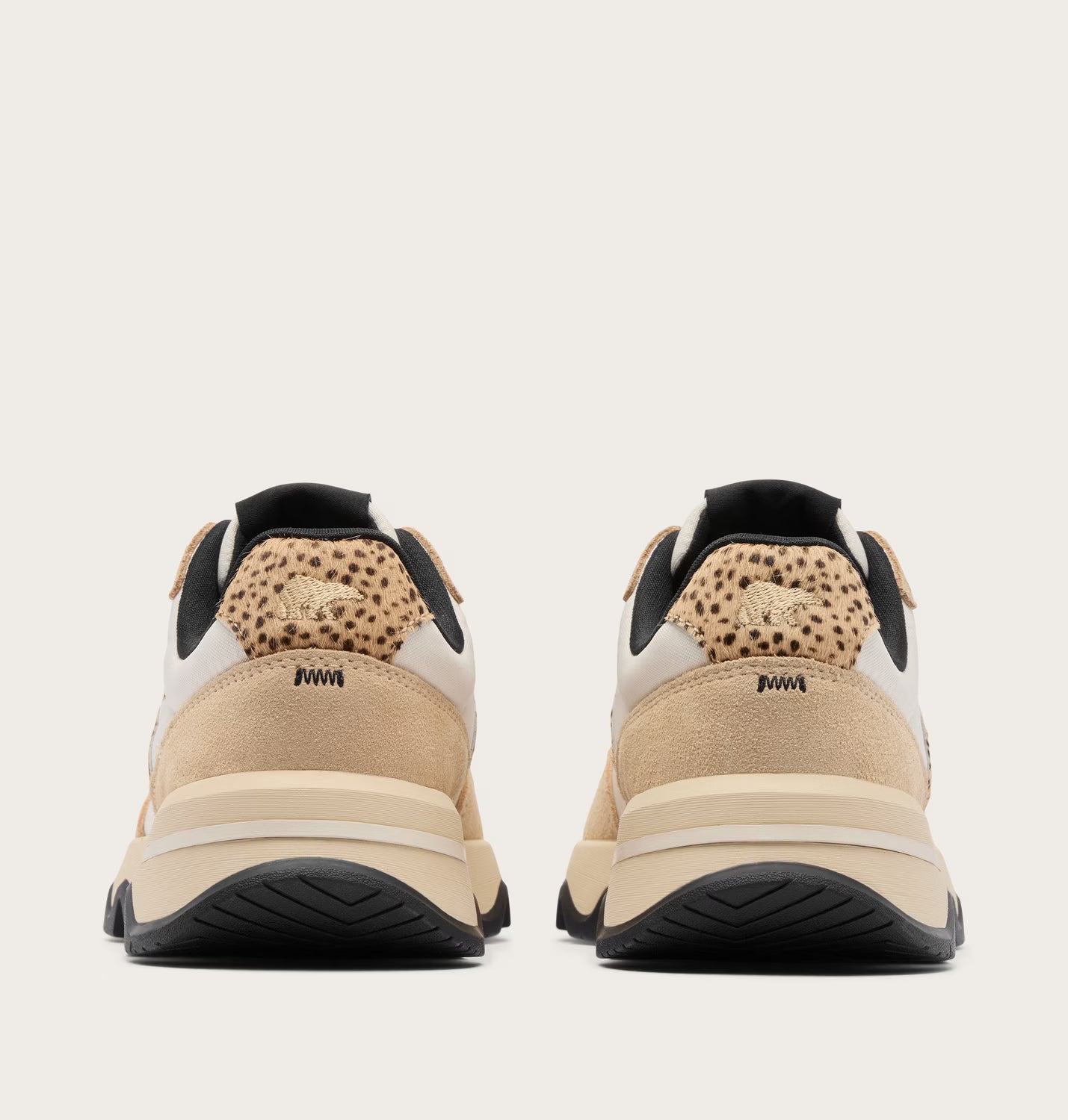 Pair of beige sneakers with black soles on a light gray background
