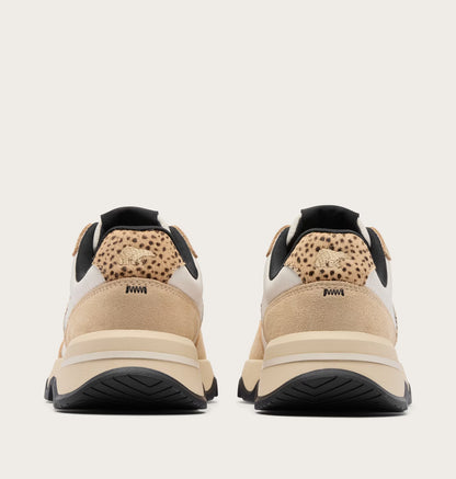 Pair of beige sneakers with black soles on a light gray background