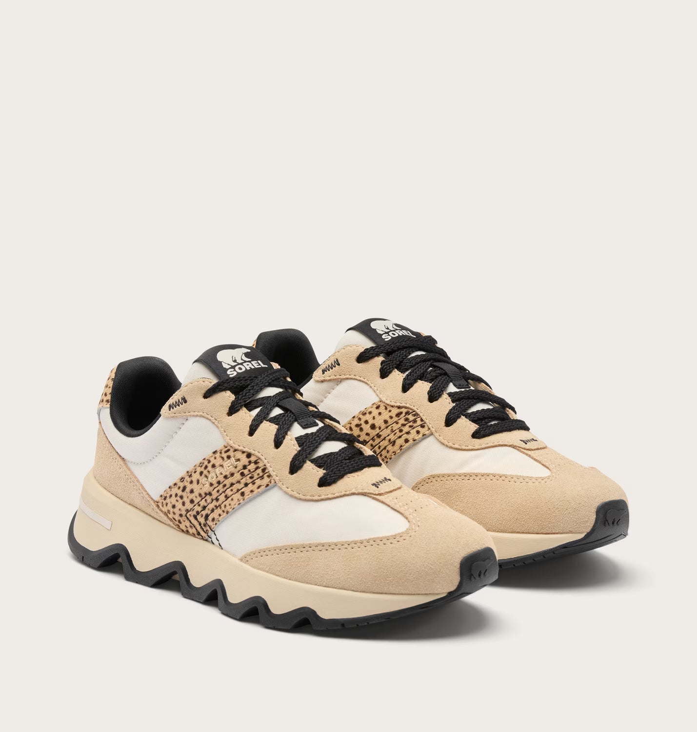 Beige and black sneakers with a patterned sole on a light beige background