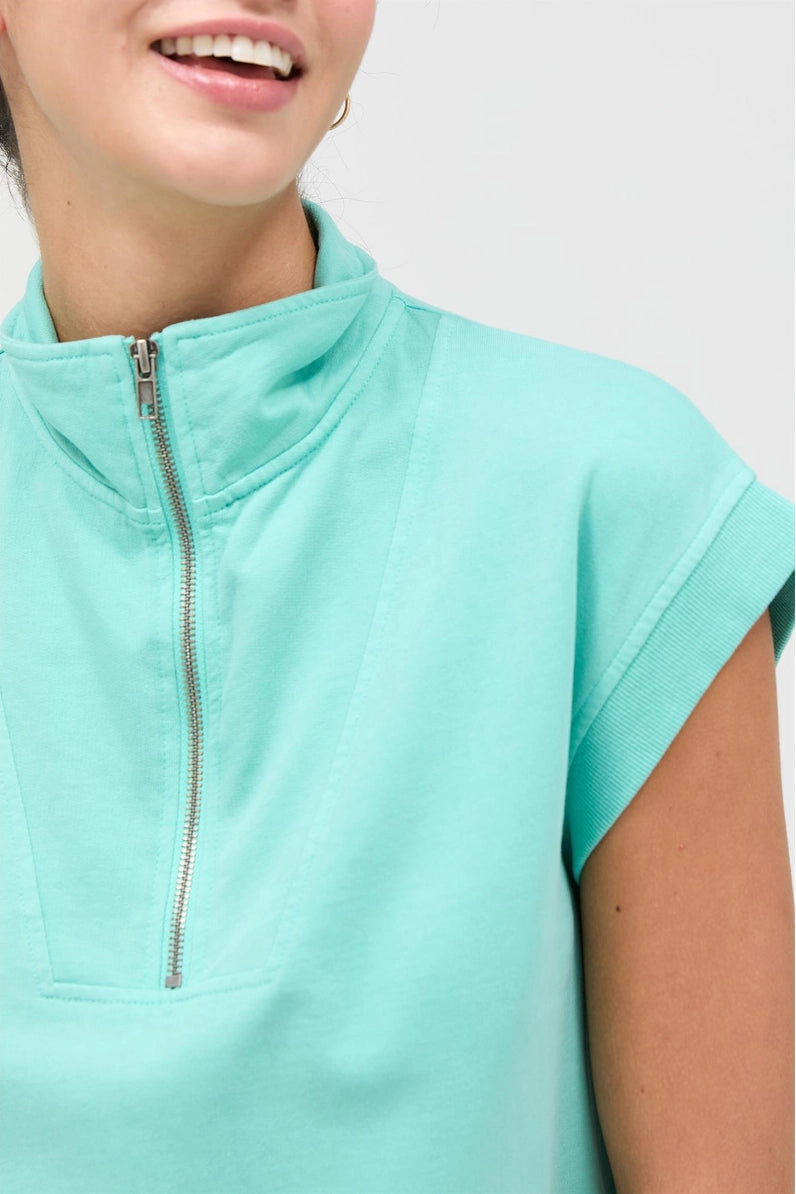Mint green zip-up top worn by a person on a white background