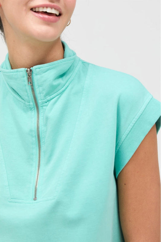 Mint green zip-up top worn by a person on a white background