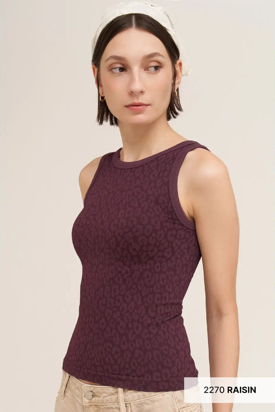 A woman wearing a sleeveless ribbed tank top in a deep plum purple color with a subtle tonal pattern, paired with light beige pants and a white headband. The image has a text overlay in the bottom right corner reading '2270 RAISIN'.