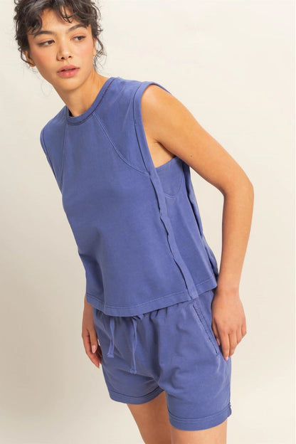 Person wearing a blue sleeveless top and shorts set on a plain background