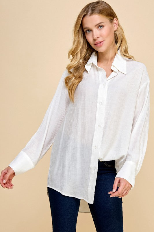 Woman wearing a white button-up shirt and dark jeans on a beige background