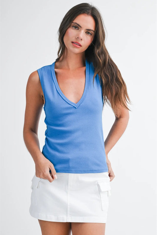 Woman wearing a blue sleeveless top and white skirt on a white background