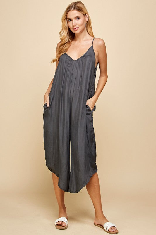 Woman wearing a dark gray sleeveless dress against a beige background