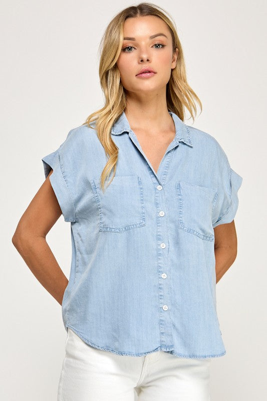 Woman wearing a light blue denim shirt against a white background