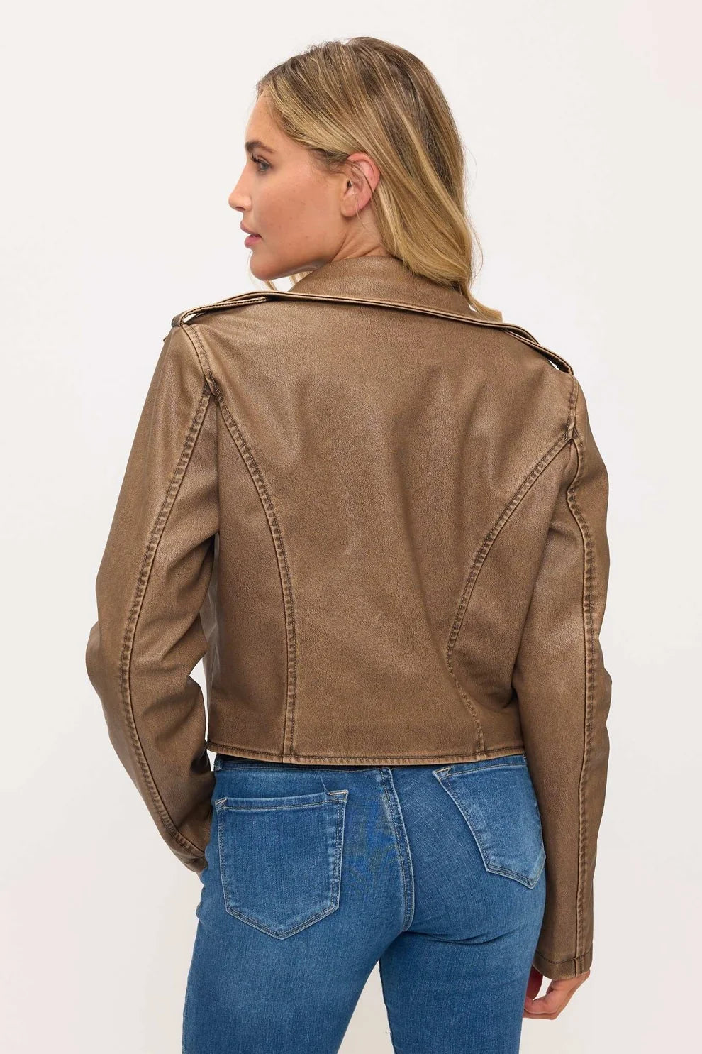 Woman wearing a brown leather jacket and blue jeans on a white background