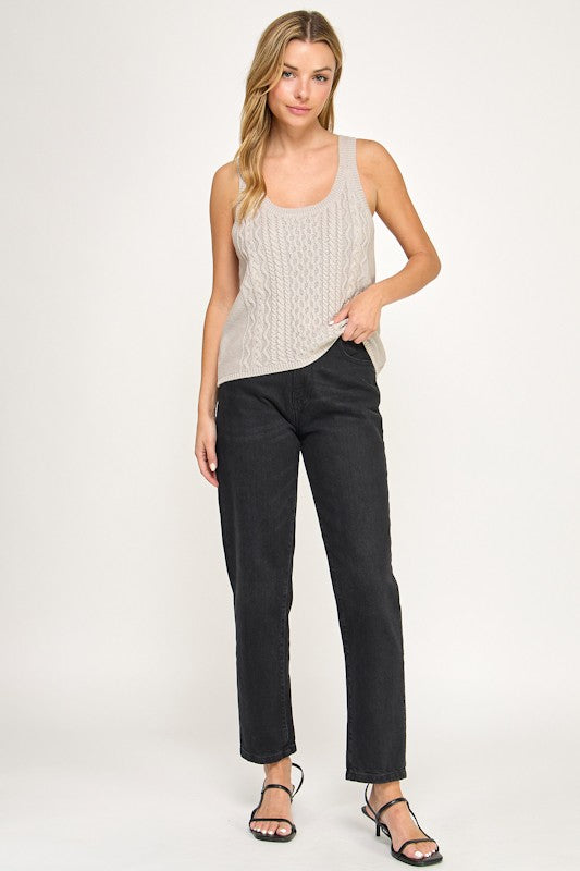 Woman wearing a beige sleeveless top and black pants on a white background