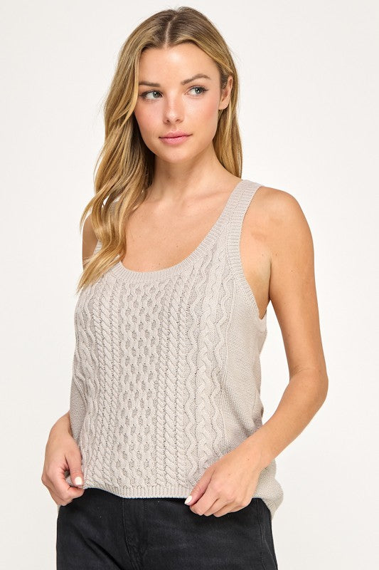 Woman wearing a beige knitted tank top against a plain background