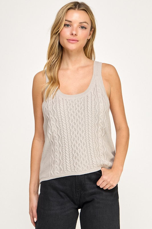 Woman wearing a beige knitted tank top against a white background