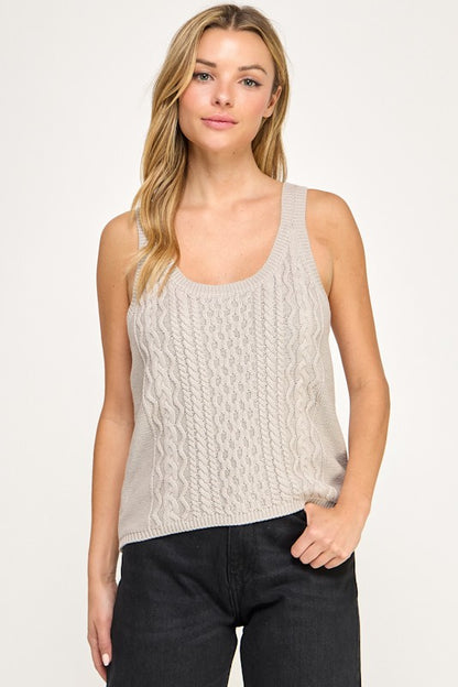 Woman wearing a beige knitted tank top against a white background