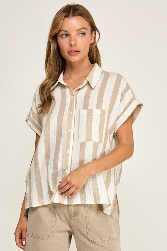 A woman wearing a short-sleeve button-up shirt with vertical beige and off-white stripes, paired with beige pants, against a plain light background.