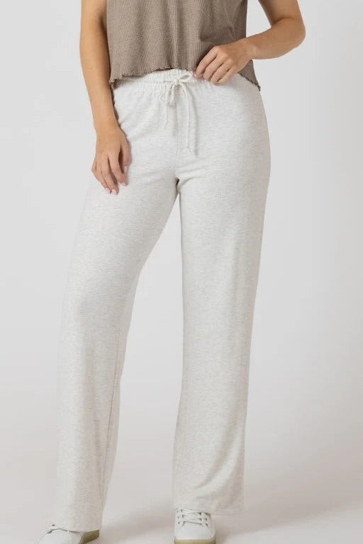 Person wearing light gray drawstring pants on a white background