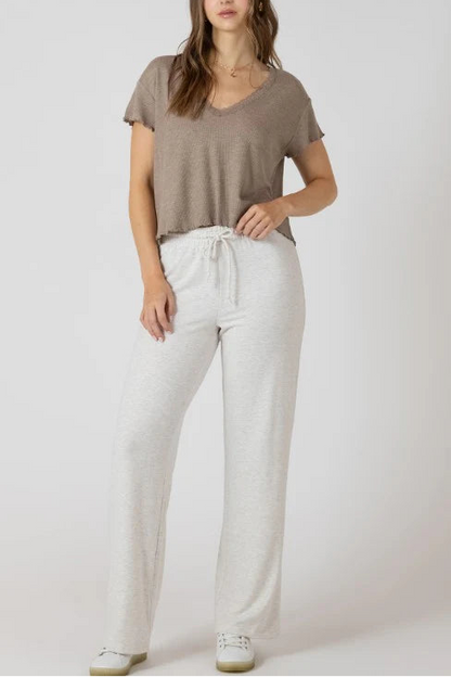 Woman wearing a brown top and white pants on a plain background
