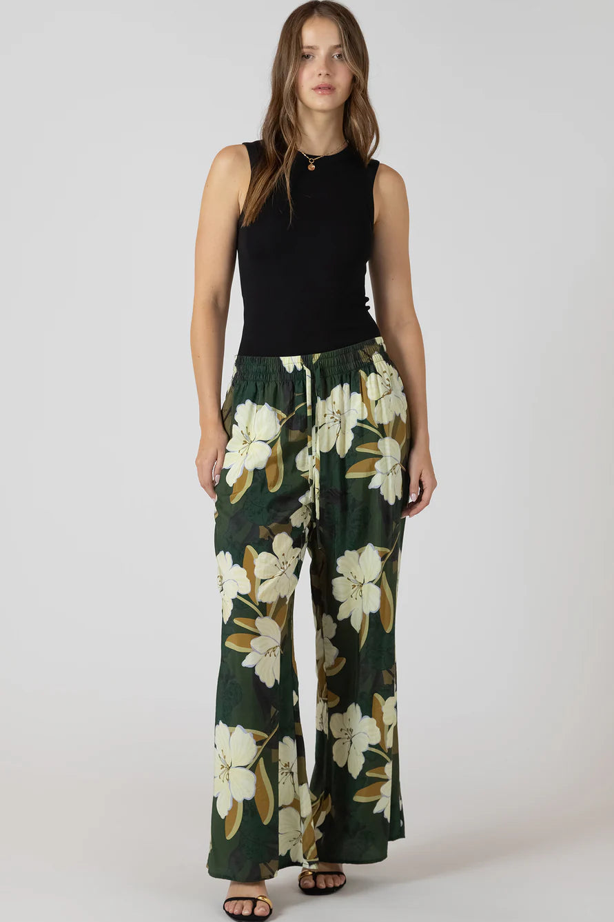 woman wearing flowy pants with flower print and black top