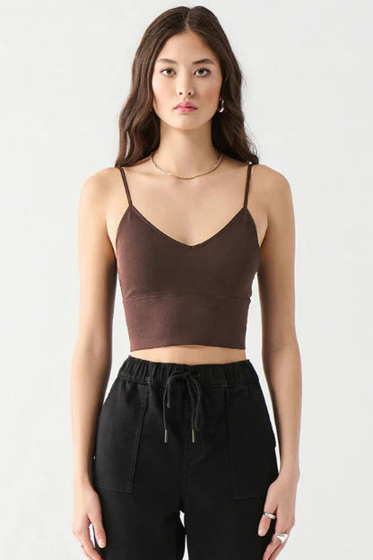 A woman modeling a dark brown spaghetti-strap crop top paired with black drawstring pants against a plain light gray studio background.
