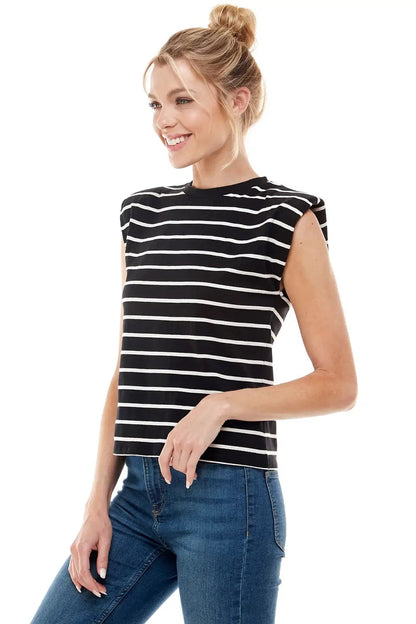 Woman wearing a black and white striped sleeveless top and blue jeans on a white background