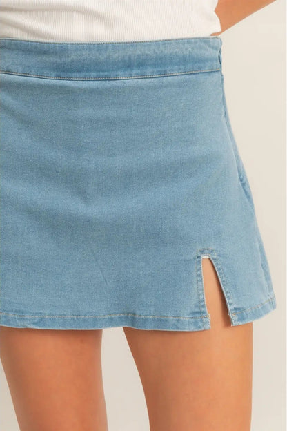 Blue denim skirt with a slit on a plain background