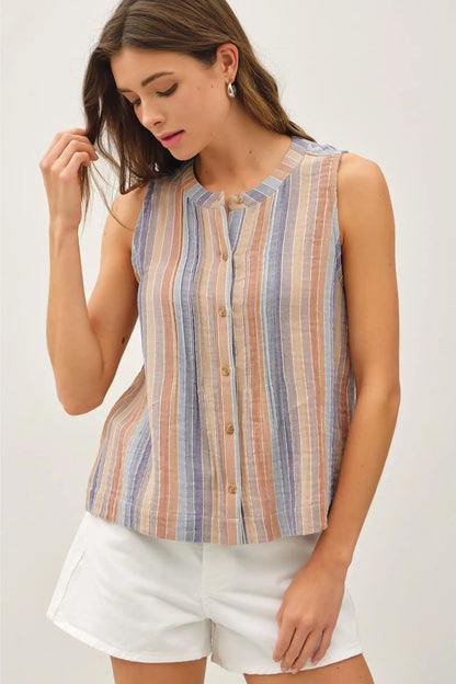 Woman wearing a sleeveless striped shirt and white shorts on a plain background