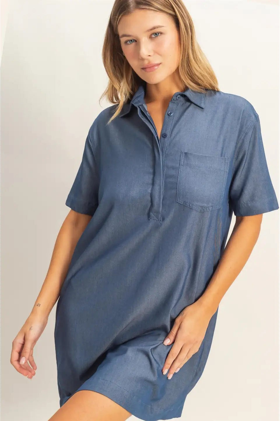Woman wearing a blue shirt dress against a plain background