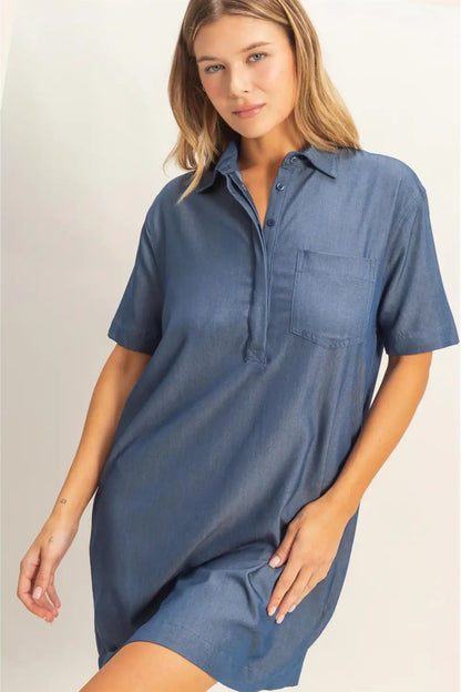 Woman wearing a blue shirt dress against a plain background