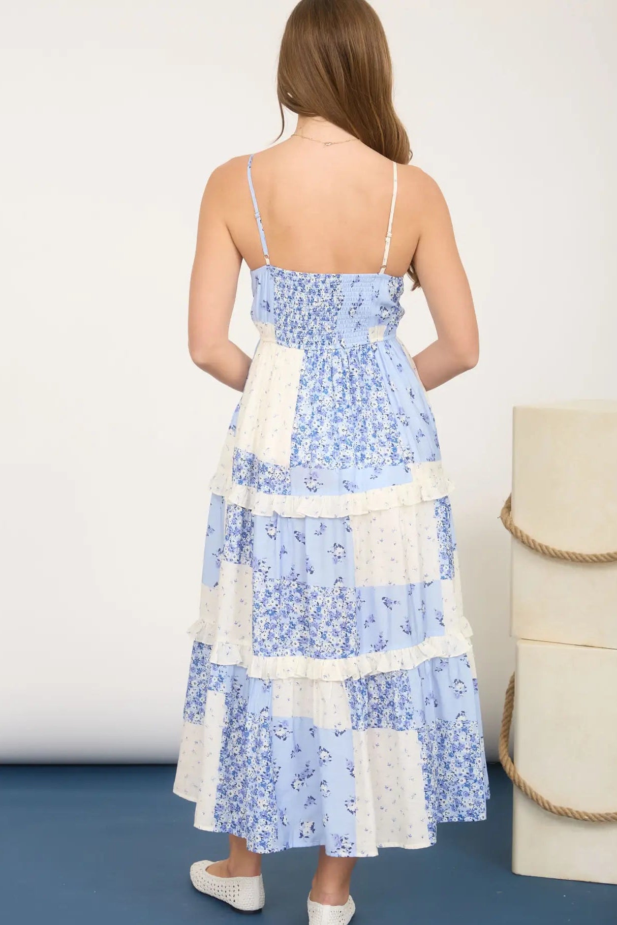 Woman wearing a blue floral dress with white accents against a white background