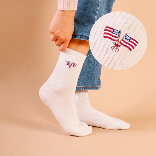 White socks with American flag design worn by a person on a beige background