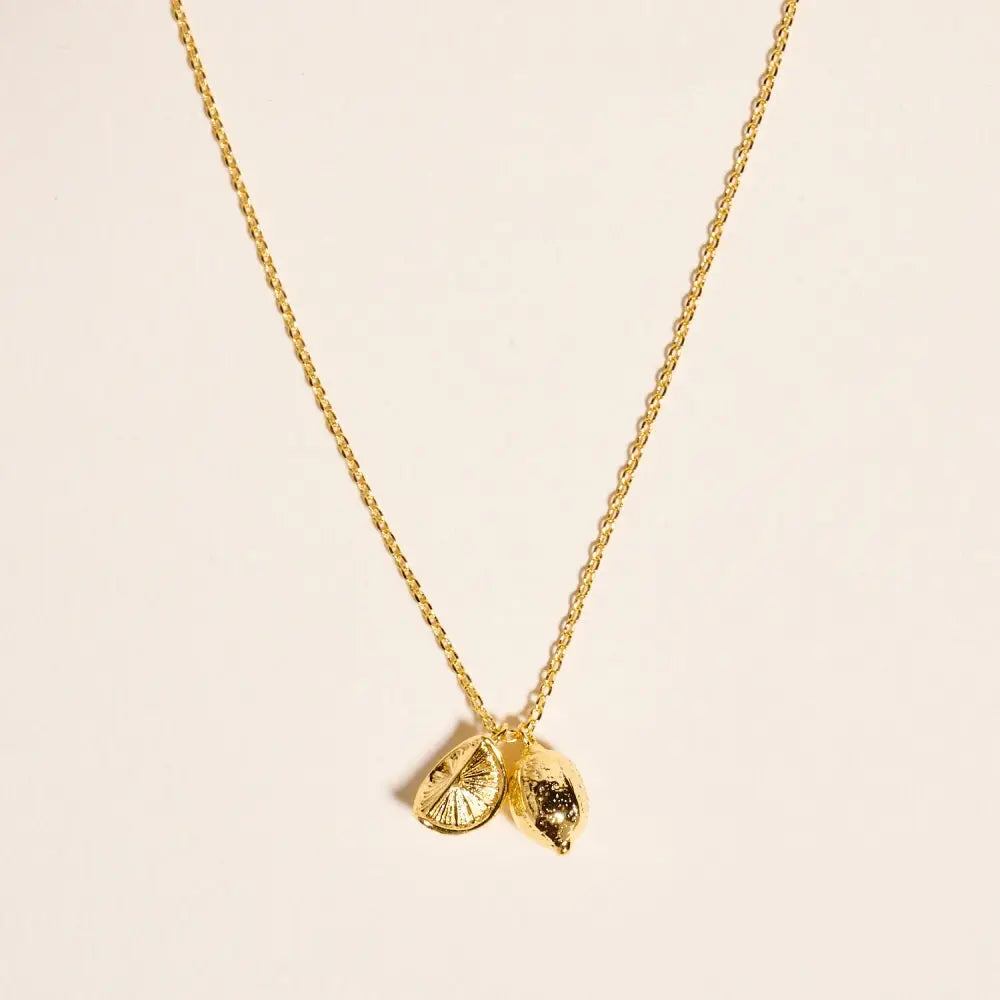 Gold necklace with a unique pendant on a beige background