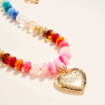 Colorful beaded necklace with a gold heart-shaped pendant on a light background