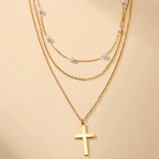 Gold necklace with a cross pendant on a beige background