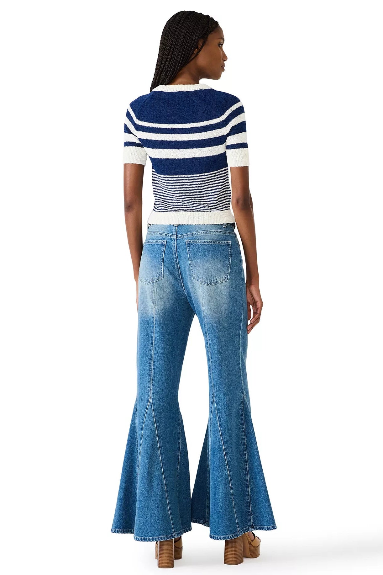 Woman wearing a striped shirt and flared jeans on a white background