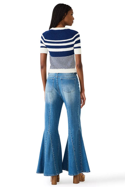 Woman wearing a striped shirt and flared jeans on a white background