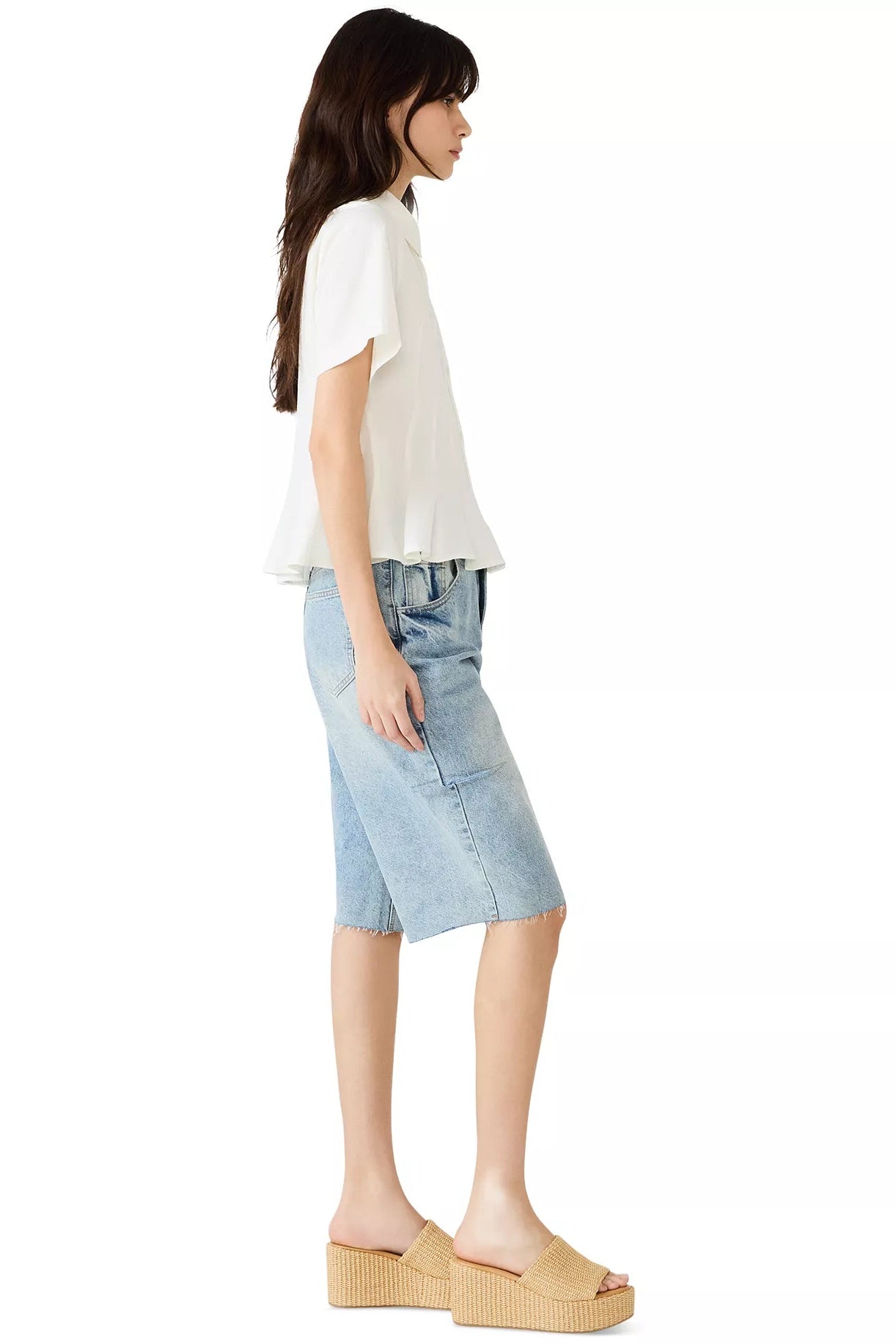 Woman wearing a white top and light blue denim skirt on a white background